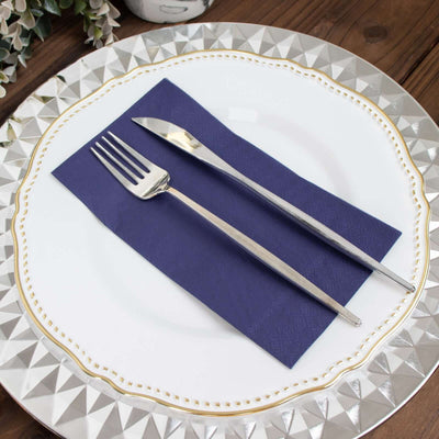 Elegant silver cutlery on a navy napkin atop a decorative plate.