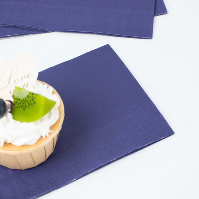 Navy blue napkins with a cupcake topped with cream and fruit garnish