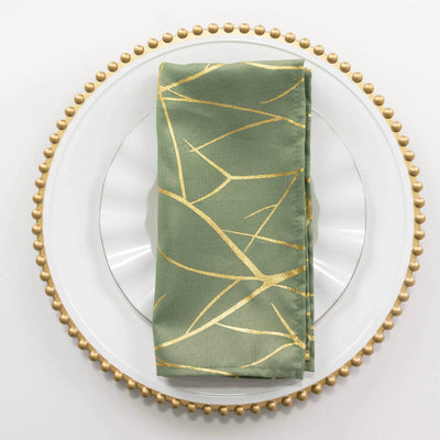 Green napkin with gold design on a decorative plate.