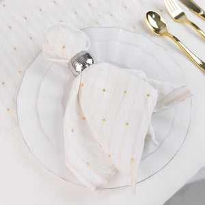 Elegant white napkin with gold dots and silver ring on a white plate setting