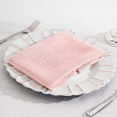 Pink linen napkin neatly folded on a decorative white plate.