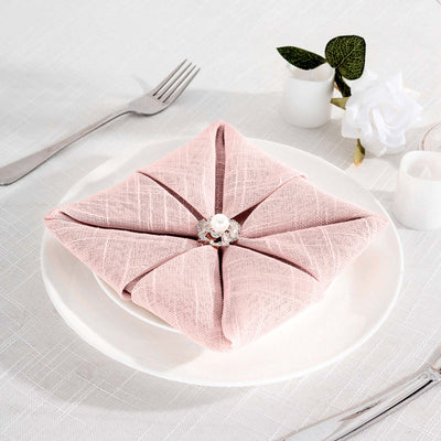 Elegant pink napkin with decorative ring on a white plate.
