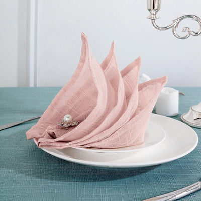 Elegant pink linen napkin displayed on a white plate at a dining table.