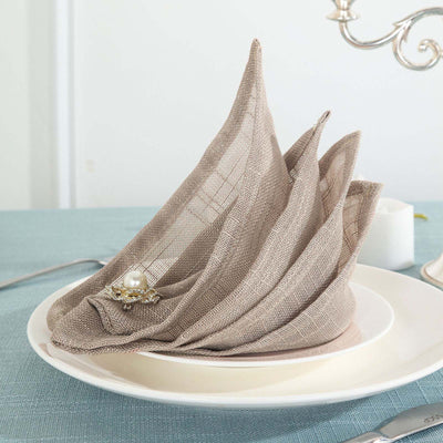 Elegant linen napkin folded in a decorative sail shape on a plate.
