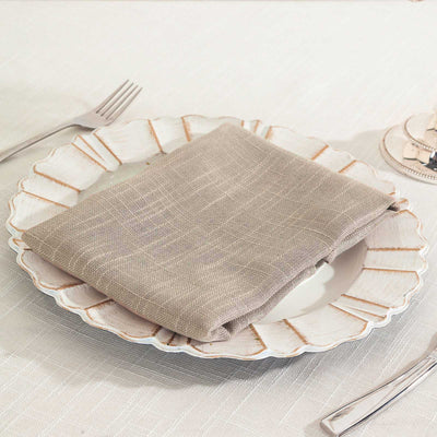 Elegant beige linen napkin folded on a decorative plate setting.