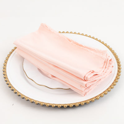 Stack of soft pink napkins on a decorative plate.