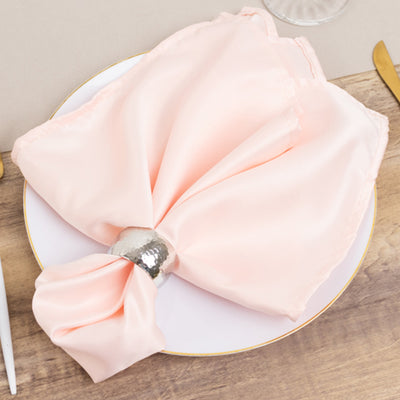Elegant pink satin napkin with a silver ring on a white plate.