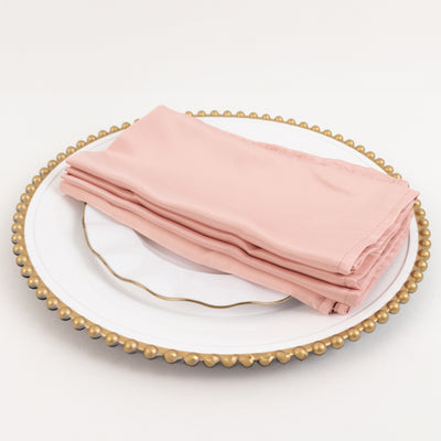 Pink napkins neatly folded on a decorative plate.