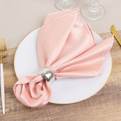 Elegant pink satin napkin with silver ring on a white plate.