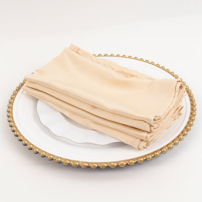 Beige napkins neatly stacked on an elegant plate.