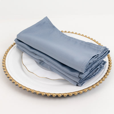 Folded blue napkins on a decorative white plate.