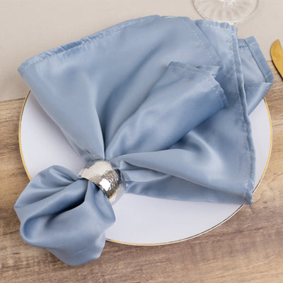Blue satin napkin elegantly tied with a silver napkin ring on a white plate.