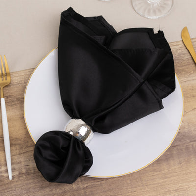Elegant black satin napkin with silver ring on a white plate.