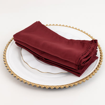 Burgundy napkins neatly folded on a decorative plate