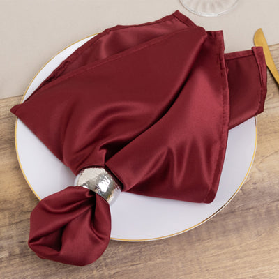 Burgundy satin napkin with silver ring on a decorative plate