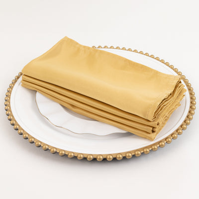 Folded golden napkins on a decorative plate.
