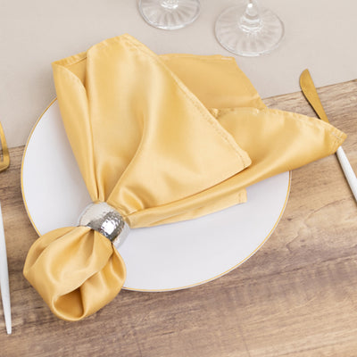 Elegant gold napkin with silver ring on a white plate. Perfect for table settings.
