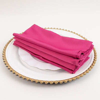 Pink napkins stacked on a decorative plate.