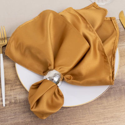 Elegant gold satin napkin elegantly arranged on a white plate.