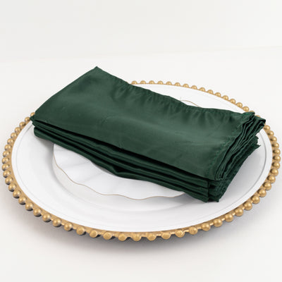 Green satin napkins stacked on a decorative plate