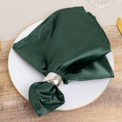 Green satin napkin with a silver napkin ring on a white plate.