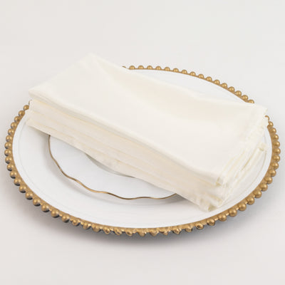 Elegant white satin napkins stacked on a decorative plate.
