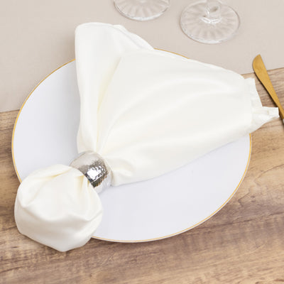 Elegant white napkin with silver ring on a decorative plate.