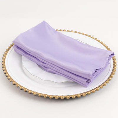 Purple satin napkins neatly stacked on a decorative plate.