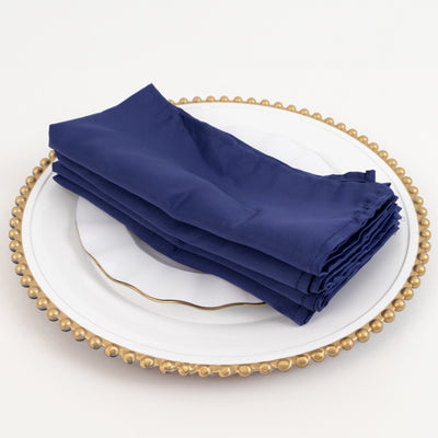 Navy blue napkins stacked on a decorative plate.