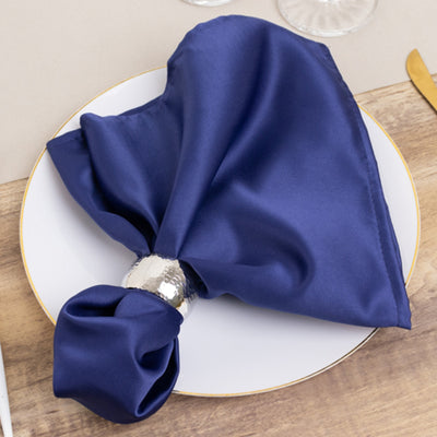 Navy satin napkin elegantly styled on a white plate with a silver napkin ring.