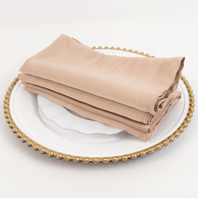 Folded beige napkins on a decorative plate.