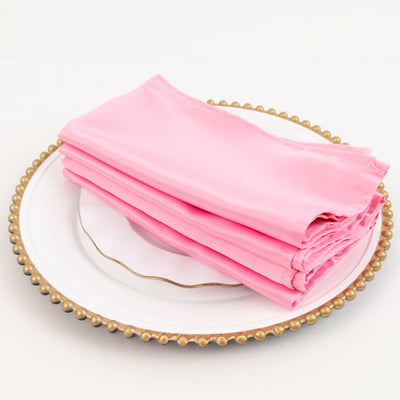 Pink silk napkins neatly folded on a decorative plate.