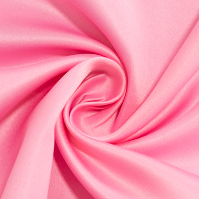 Pink satin fabric swirl, showcasing smooth texture and vibrant color.
