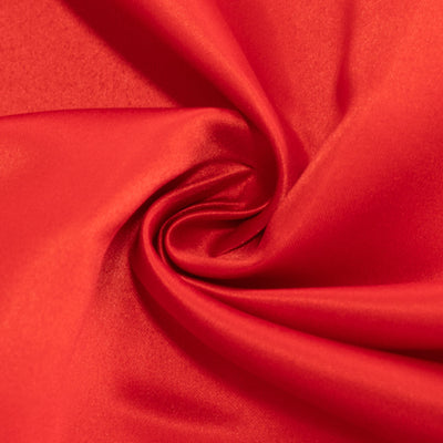 Smooth red fabric texture in a swirling pattern.