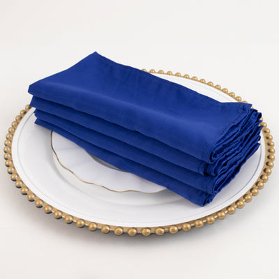 Folded navy blue napkins on an elegant white plate with a gold rim.