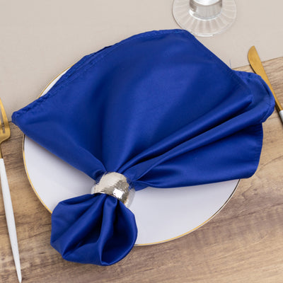 Elegant blue napkin elegantly tied with a silver holder on a white plate.
