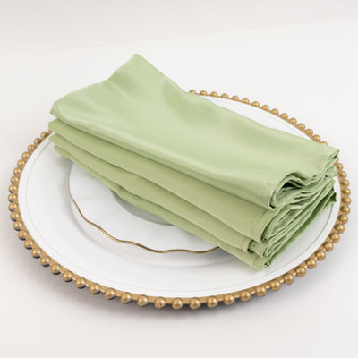 Green satin napkins neatly folded on a decorative plate.