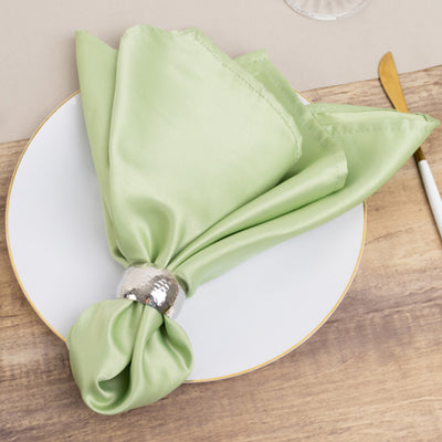 Elegant green satin napkin tied with a silver ring on a plate.