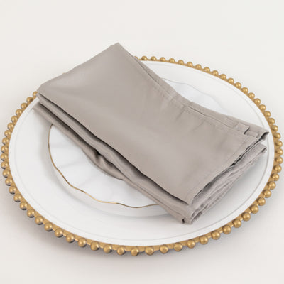 Gray cloth napkins neatly folded on a decorative plate.