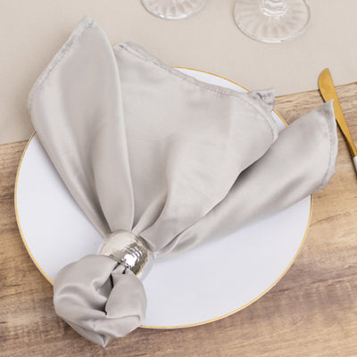 Elegant gray napkin with silver ring on a white plate.