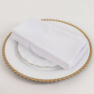 White napkins neatly stacked on an elegant plate with a gold rim.
