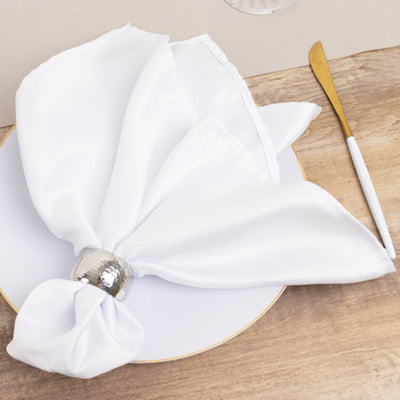 Elegant white napkin tied with a silver ring on a plate.