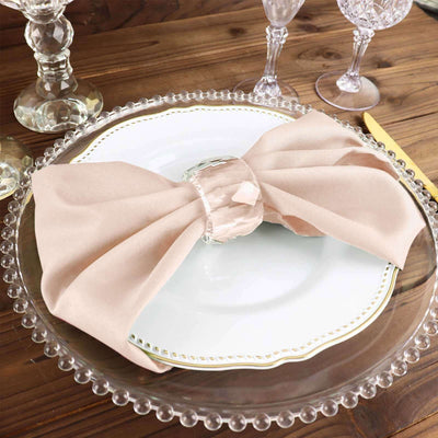 Elegant beige napkin elegantly tied on a decorative plate for dining table setup.