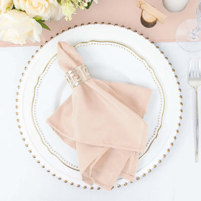Elegant blush napkin elegantly folded on a decorative plate with gold accents.