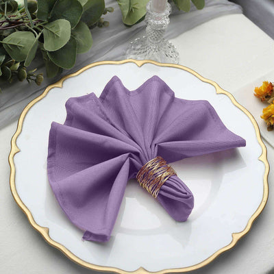 Purple cloth napkin elegantly folded on a decorative plate.