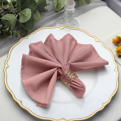 Pink fabric napkin elegantly folded on a decorative plate.