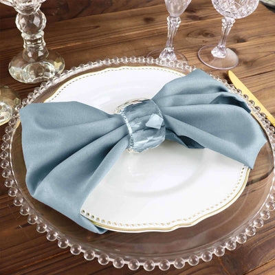 Elegant blue napkin tied with a crystal ring on a decorative plate.