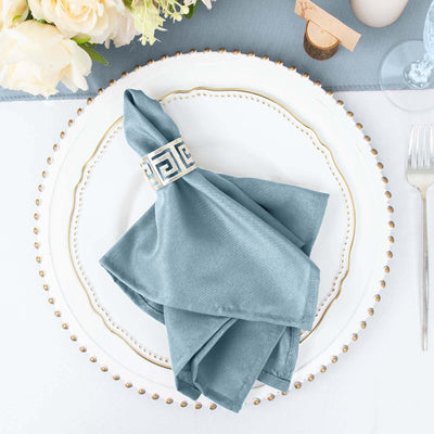 Elegant blue napkin with decorative ring on a white plate setting.