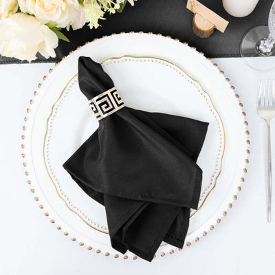 Black napkin with decorative band on elegant plate setting.