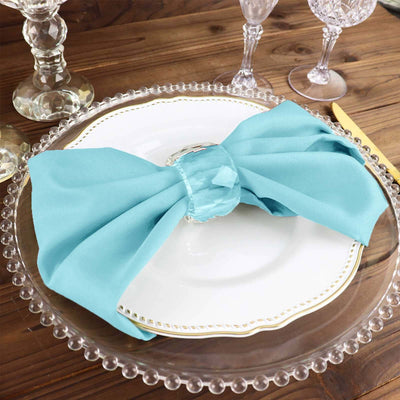 Turquoise satin napkin elegantly tied on a decorative plate.